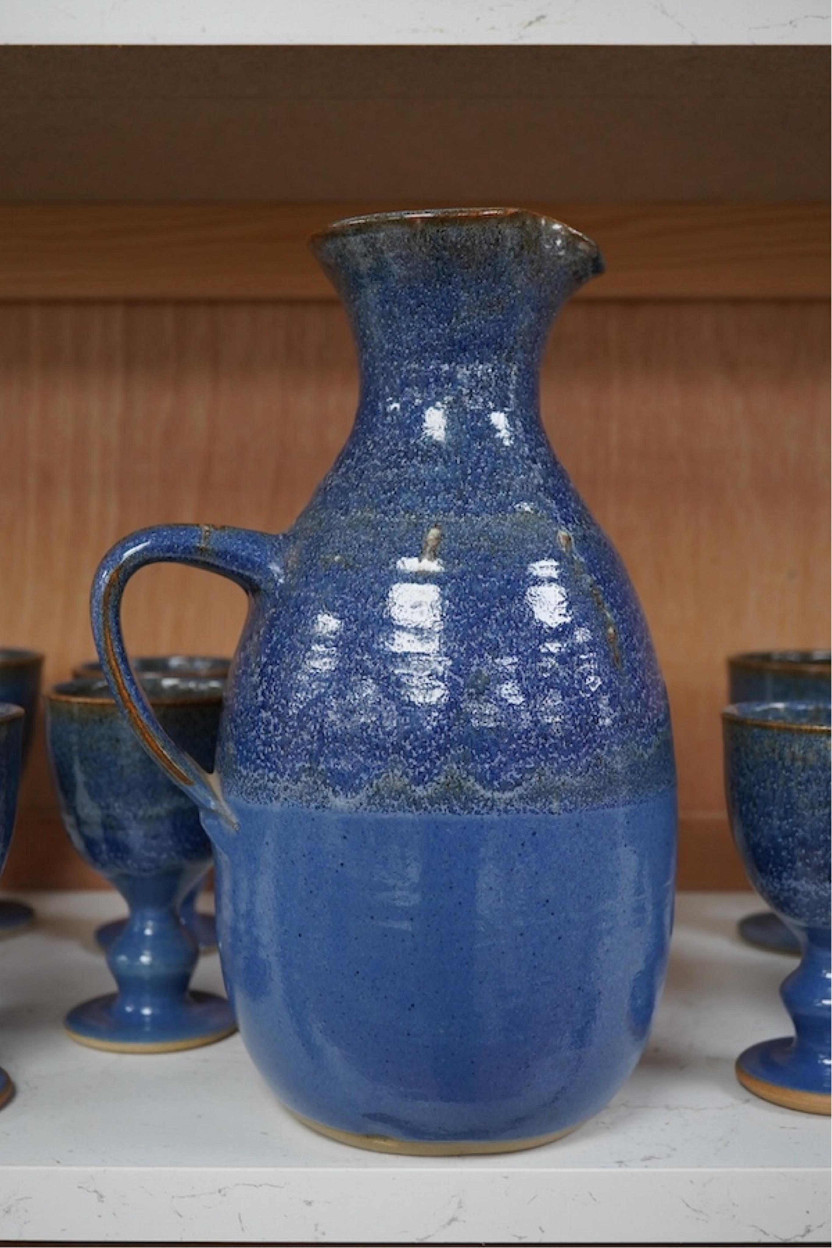 A Canterbury pottery, blue glaze jug and twelve goblets, jug 28cm high. Condition - fine chip to one goblet